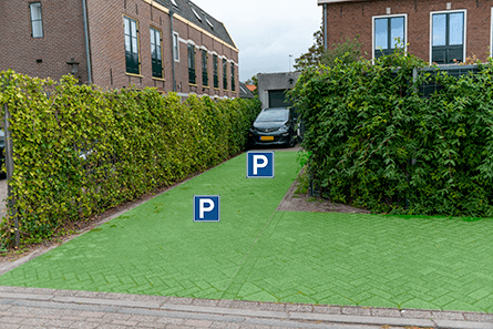 Extra parkerenplekken tussen de groene schutting met klimplanten en rekwerk met klimplanten